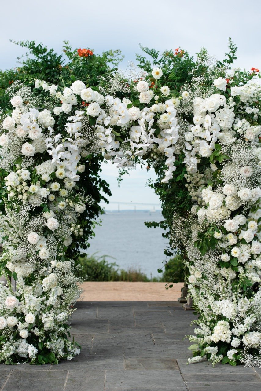 white floral arch with beach backdrop